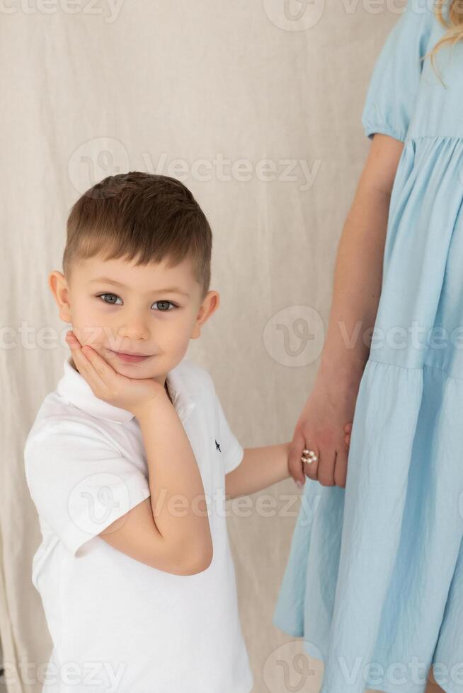 cute little boy stands next to pregnant mom's belly. mom and son hold hands. family concept photo