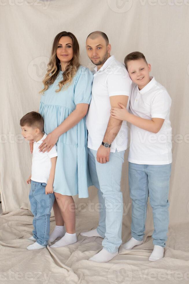 young pregnant woman with her family at home. parents hug their sons. beautiful family photo