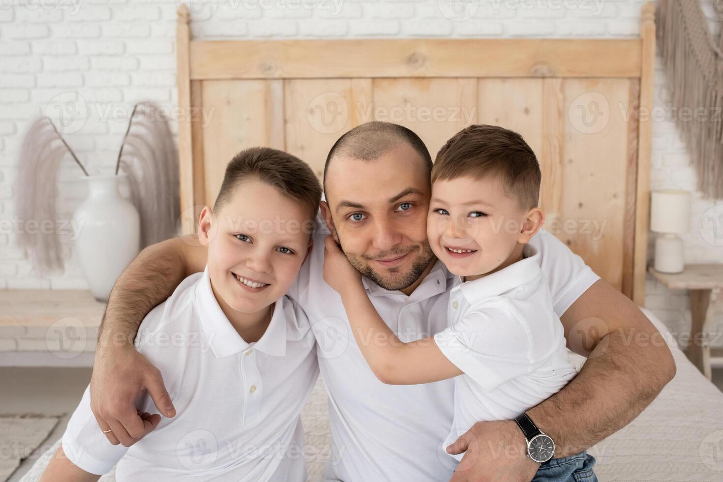dad with two sons play in a large beautiful bedroom with large windows. happy family in a beautiful light interior. boho style photo