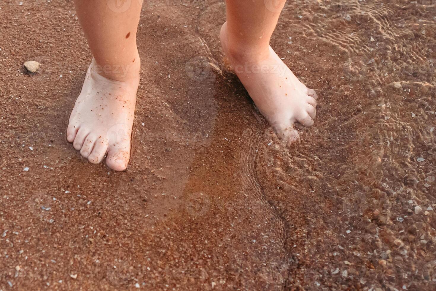 children's feet stand on the sea sand, on the coast. family vacation at sea photo