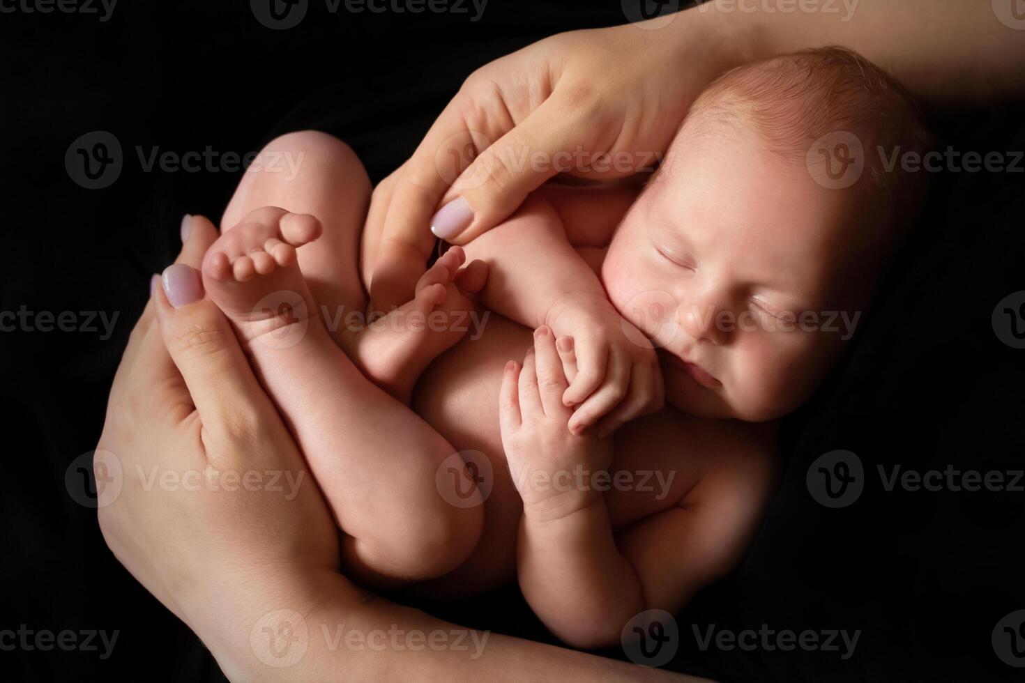 close-up of a child in the arms of a parent on a black background. concept of parenthood and care. minimalistic baby photography photo