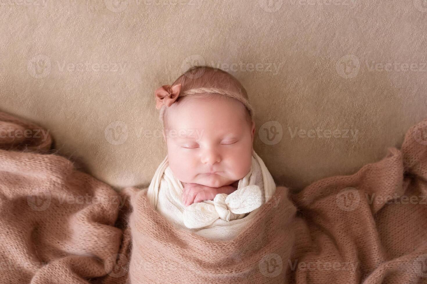 a beautiful baby in a cap sleeps on a beige background covered with a soft, fluffy blanket. close-up portrait photo