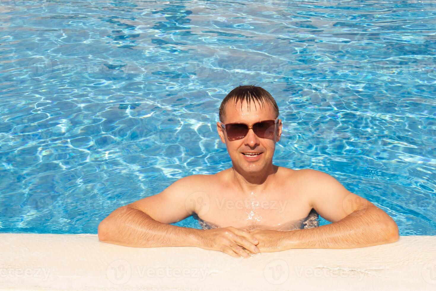 man swims and has fun near a beautiful pool at a resort during vacation. blue background, sea background photo