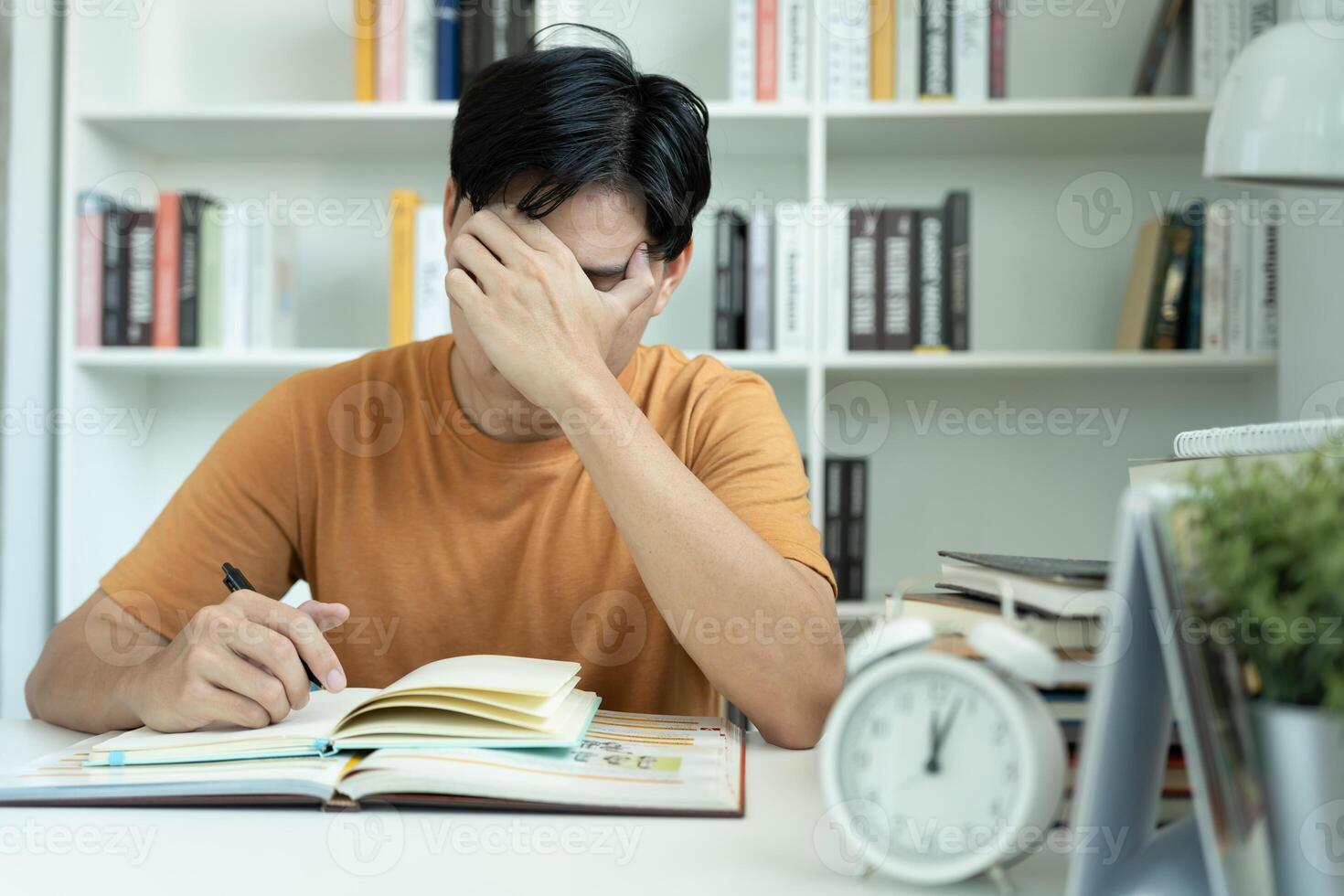 Asian student man have anxiety because of exams, male prepare for test and learning lessons in the library. stress, despair, haste, misunderstanding reading, discouraged, expectation, knowledge, tired photo