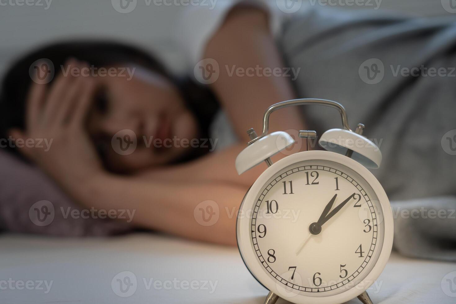 asian woman in bed late trying to sleep suffering insomnia, sleepless or scared in a nightmare, looking sad worried and stressed. Tired and headache or migraine waking up in the middle of the night. photo
