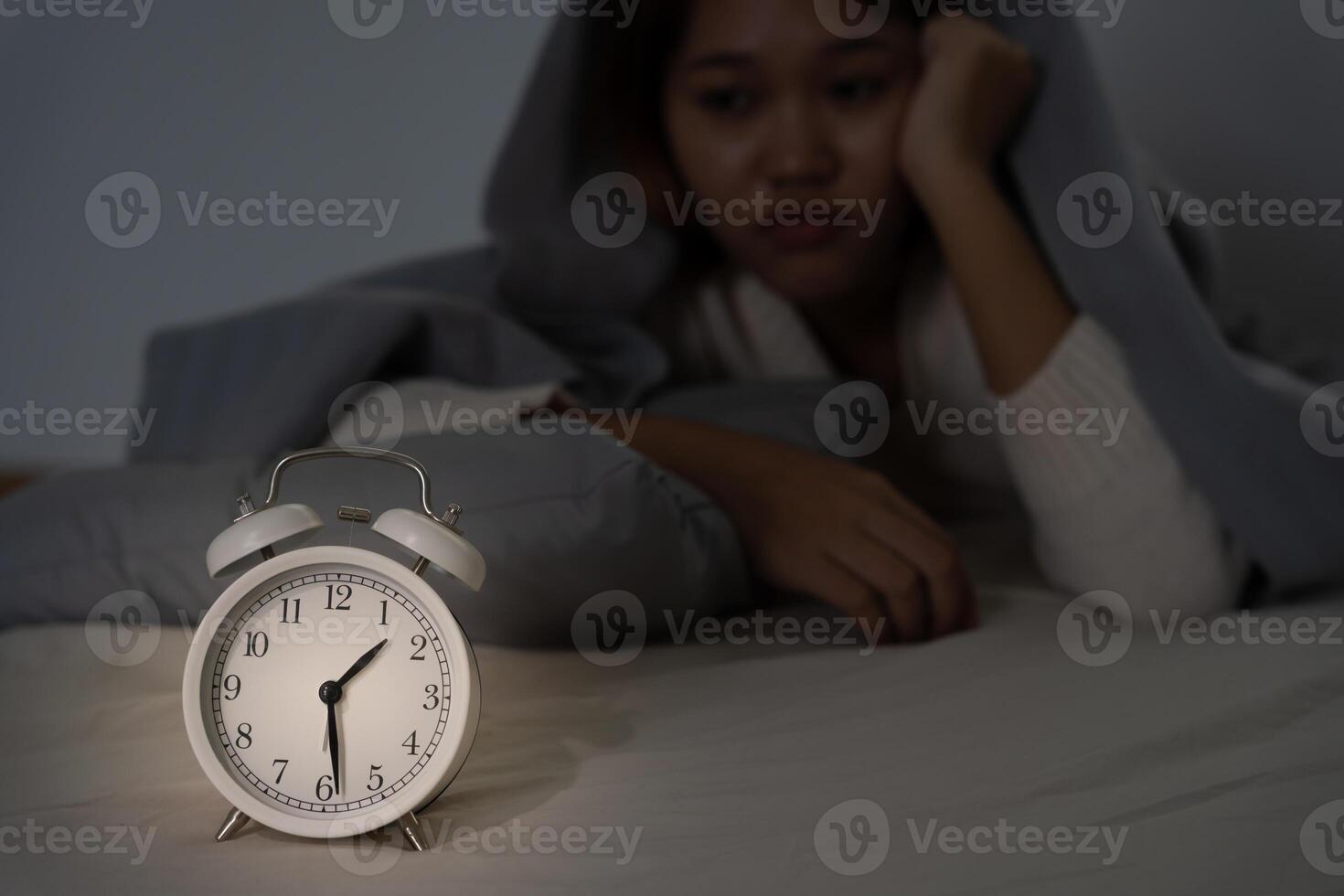asian woman in bed late trying to sleep suffering insomnia, sleepless or scared in a nightmare, looking sad worried and stressed. Tired and headache or migraine waking up in the middle of the night. photo