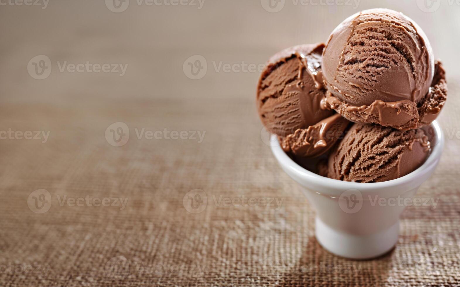 Tasty chocolate ice cream scoops in white ceramic bowl on brown textile surface, background with copy space. Delicious dessert, rustic cafe. photo