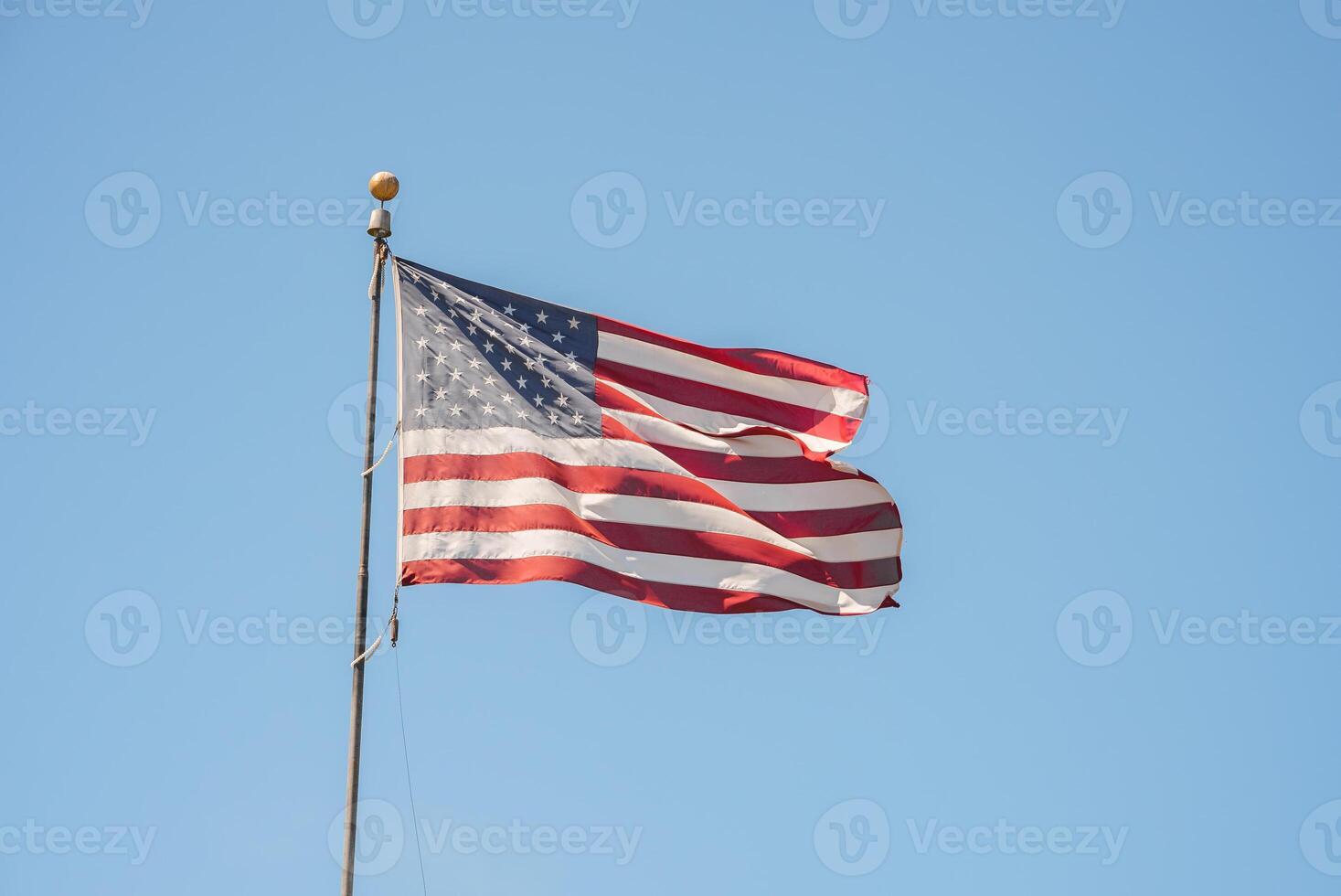 Iconic US flag flying against a blue sky in San Francisco. Symbolic 50 stars and 13 stripes design, perfect for patriotic, tourist, or landmark concepts. photo