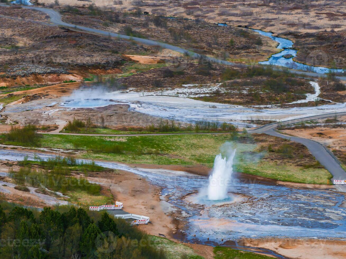 Aerial View of Erupting Geyser in Icelandic Valley with Winding River photo