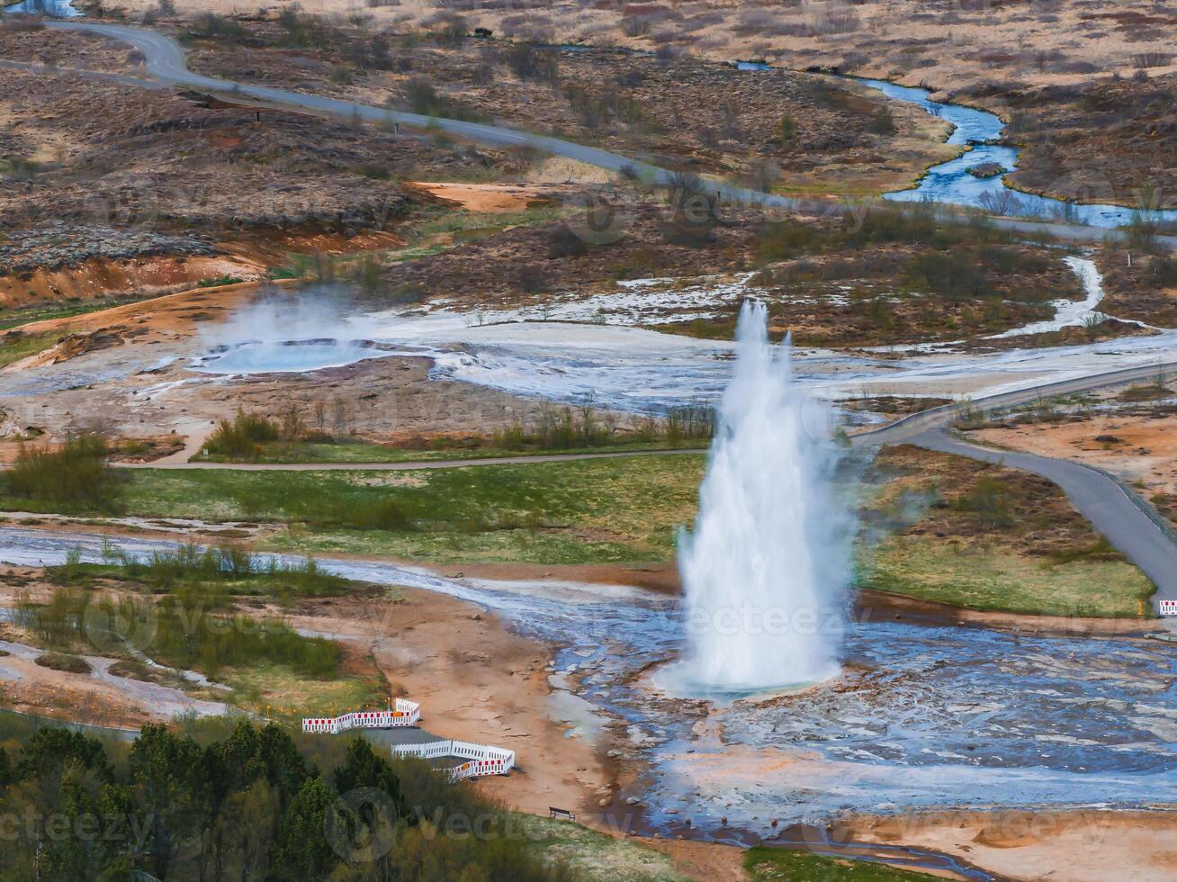 Aerial View of Erupting Geyser in Iceland with Surrounding Landscape photo