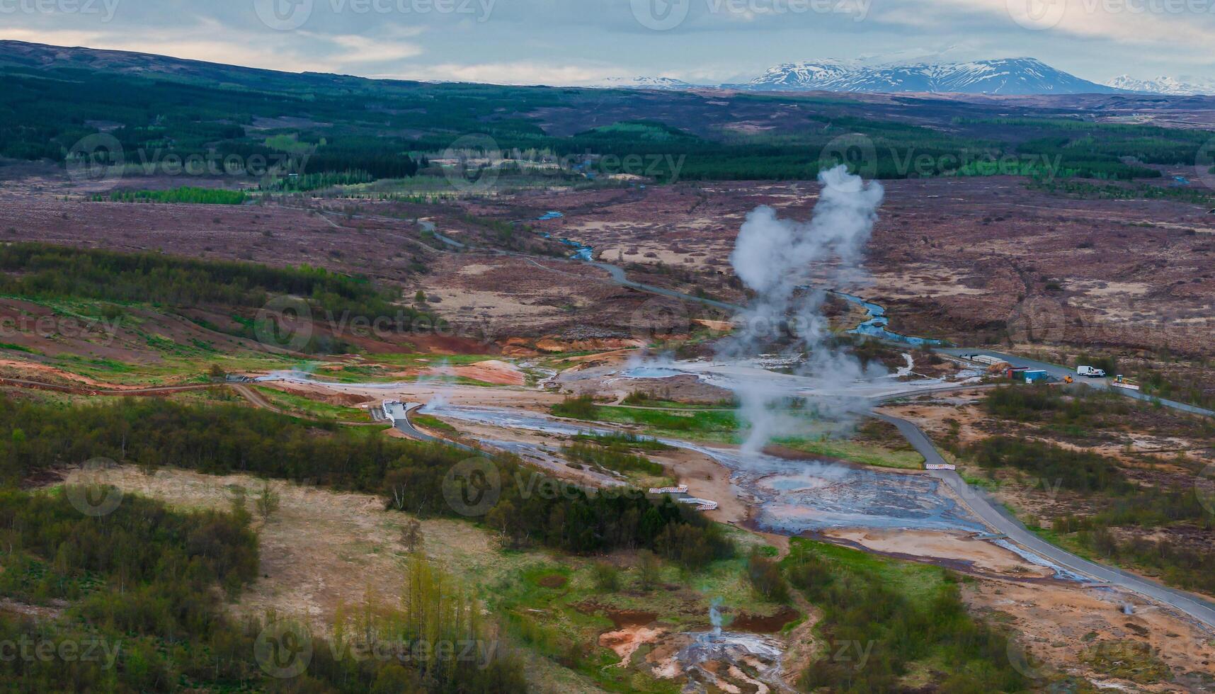 Aerial View of Erupting Geyser in Icelandic Valley Surrounded by Hills photo