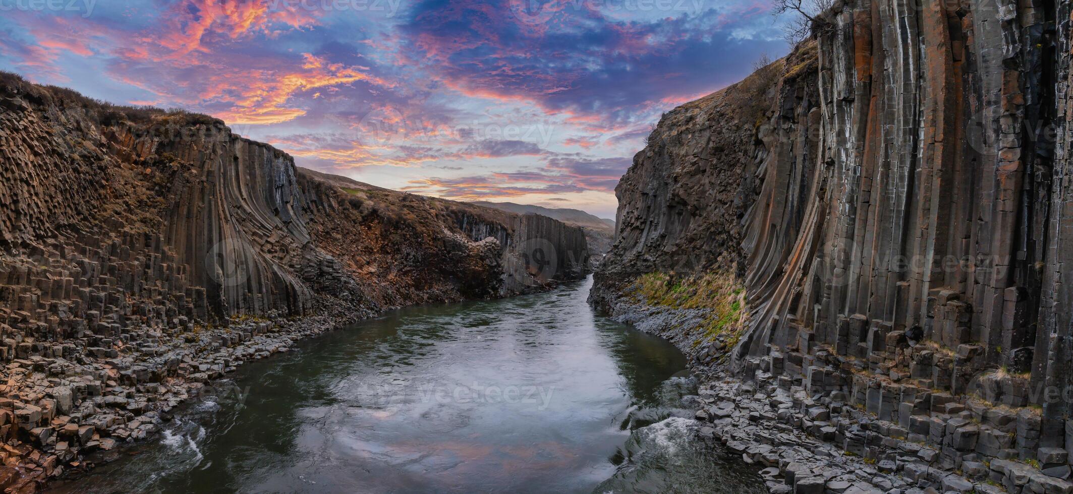 Scenic Canyon with Basalt Columns and Reflective River at Sunset in Iceland photo