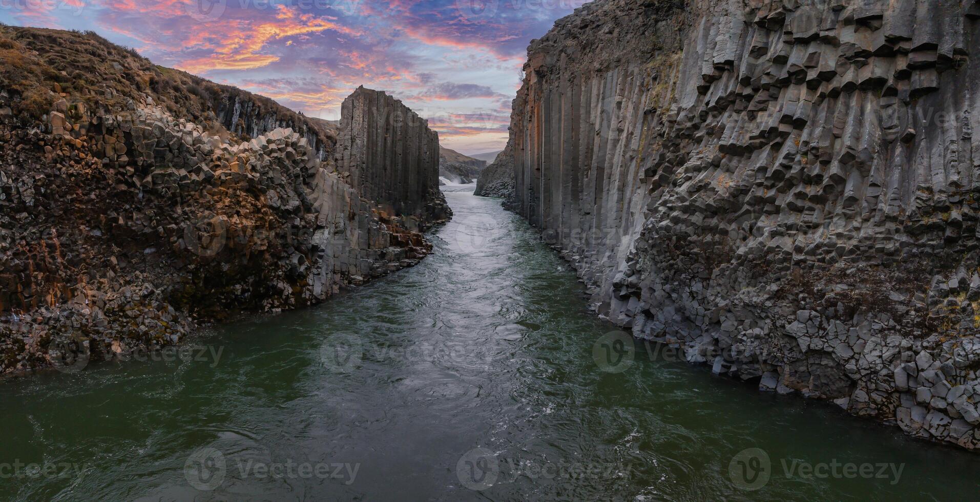 Serene River Flowing Through Basalt Column Canyon Under Vibrant Sky in Iceland photo