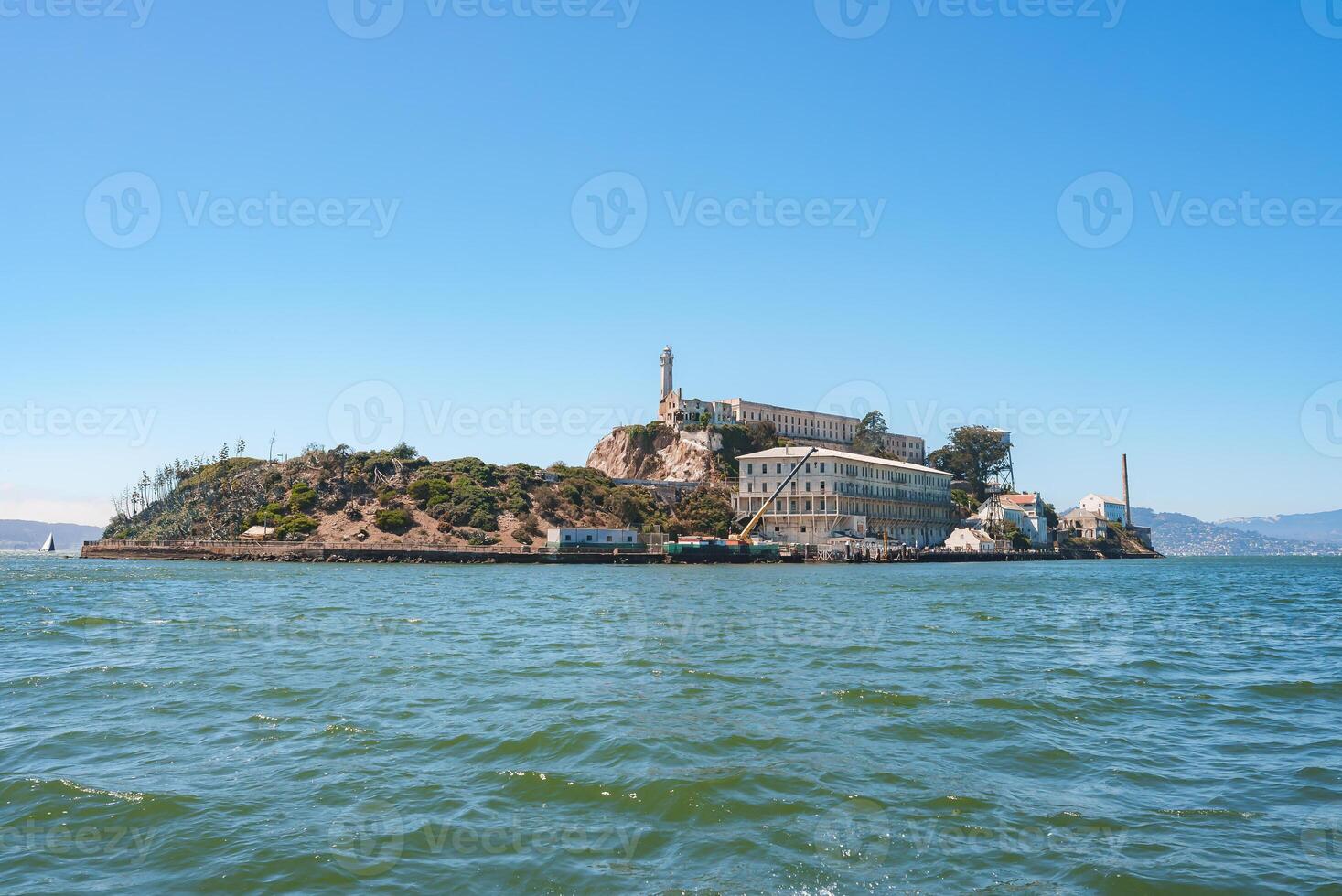 Sunny view of Alcatraz Island in San Francisco Bay, California, USA. Features former prison complex with main cellhouse, lighthouse, and serene waters. photo