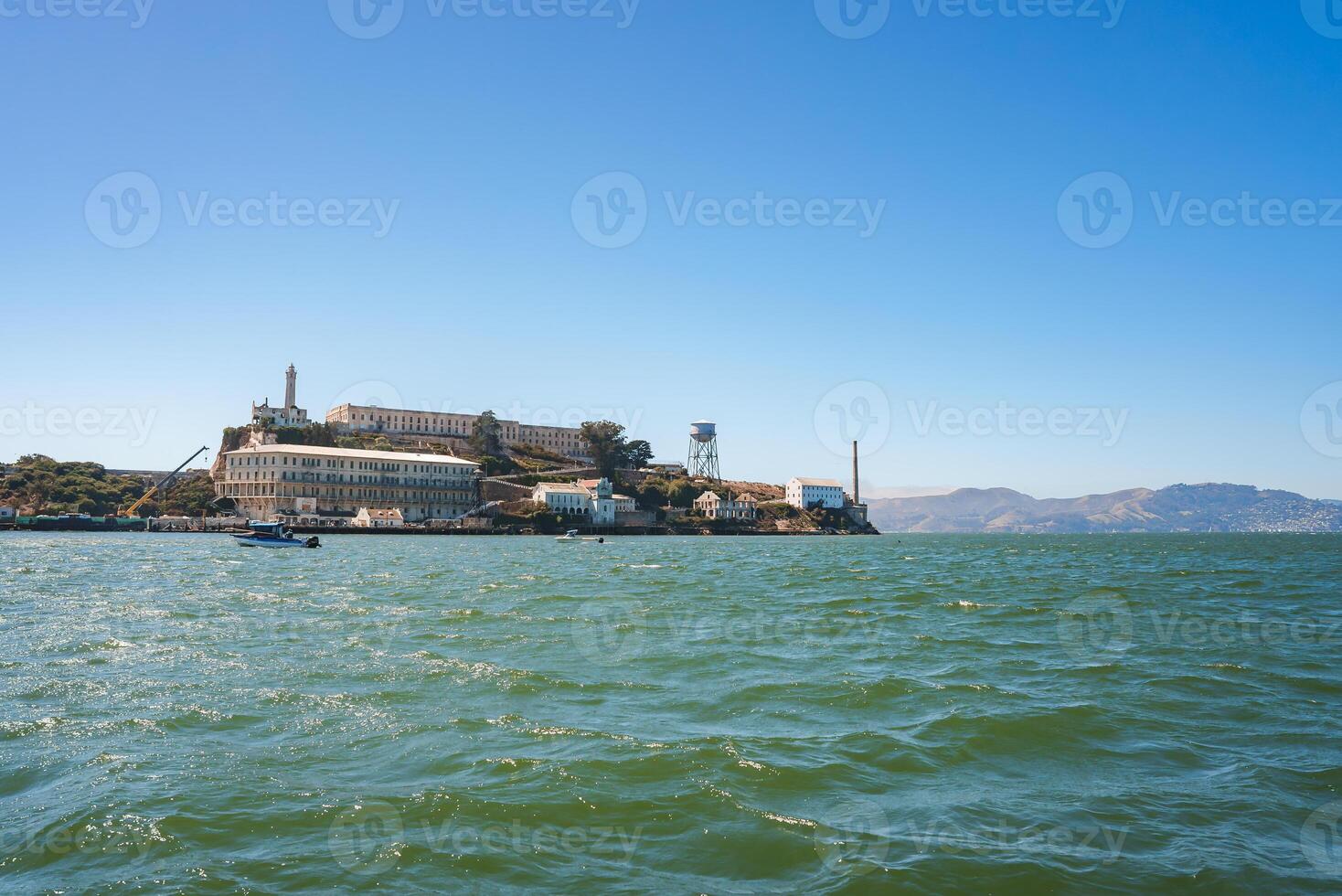 Alcatraz Island in San Francisco Bay, California, USA. View from the water, showcasing the infamous former prison turned museum with a lighthouse, waters, and rolling hills in the background. photo