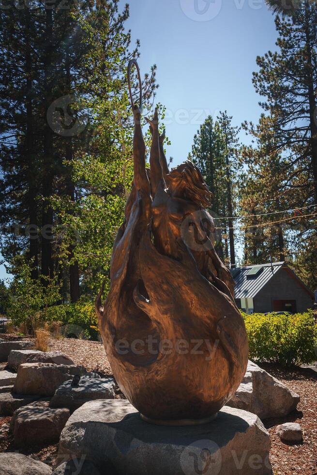 Dynamic bronze sculpture in outdoor setting with pine trees, glowing in sunlight. Intricate details and graceful form create a peaceful, contemplative atmosphere in Tahoe. photo