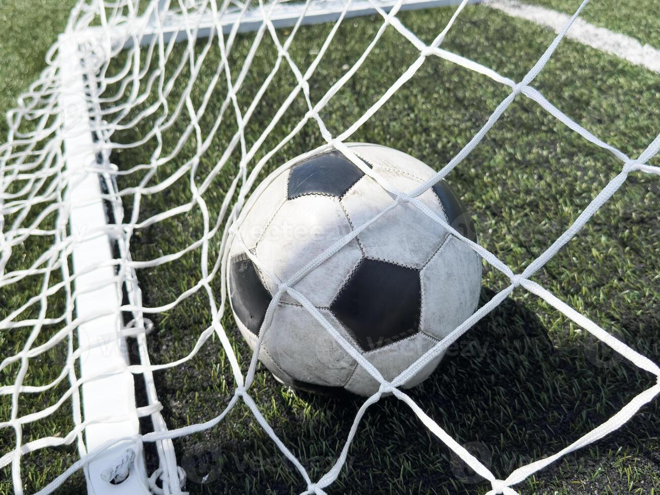 Soccer football in Goal net with green grass field. For sport concept. photo