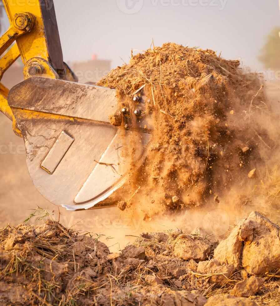 Close-up of excavator at construction site. Backhoe digging soil for earthwork and construction business. Excavating machine at work. Heavy machinery for earth moving and construction site development photo