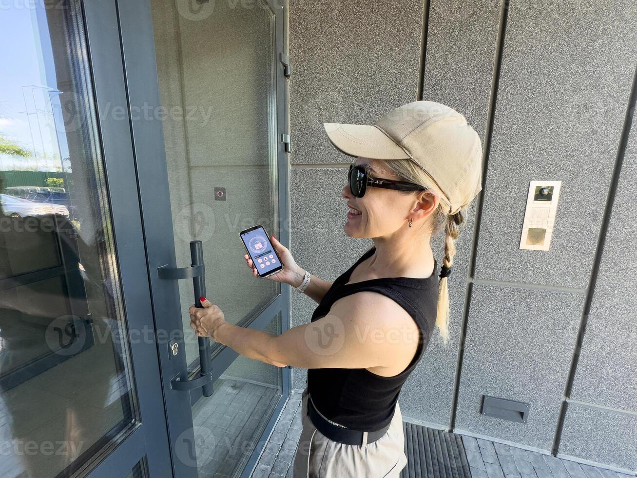 Close up of woman using intercom at building entrance. photo