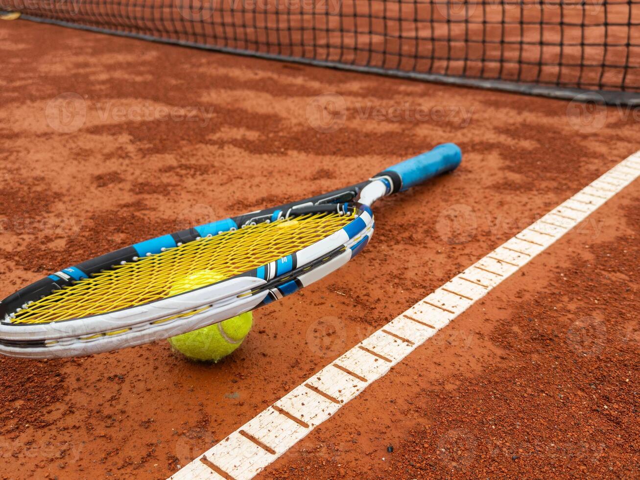 Balls and racket are lying on clay brown professional tennis court Close up of tennis balls and racket on dross at tennis court on the playground. Sport concept. Perspective up top view photo