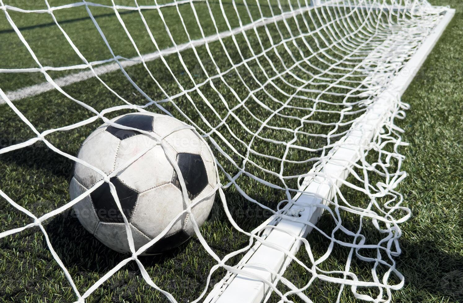Soccer football in Goal net with green grass field. For sport concept. photo