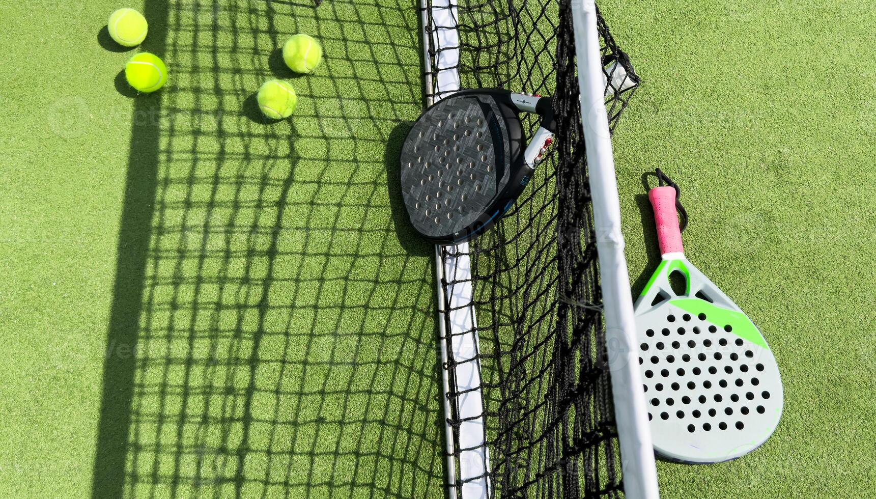 Paddle tennis racket, ball and net on the grass photo