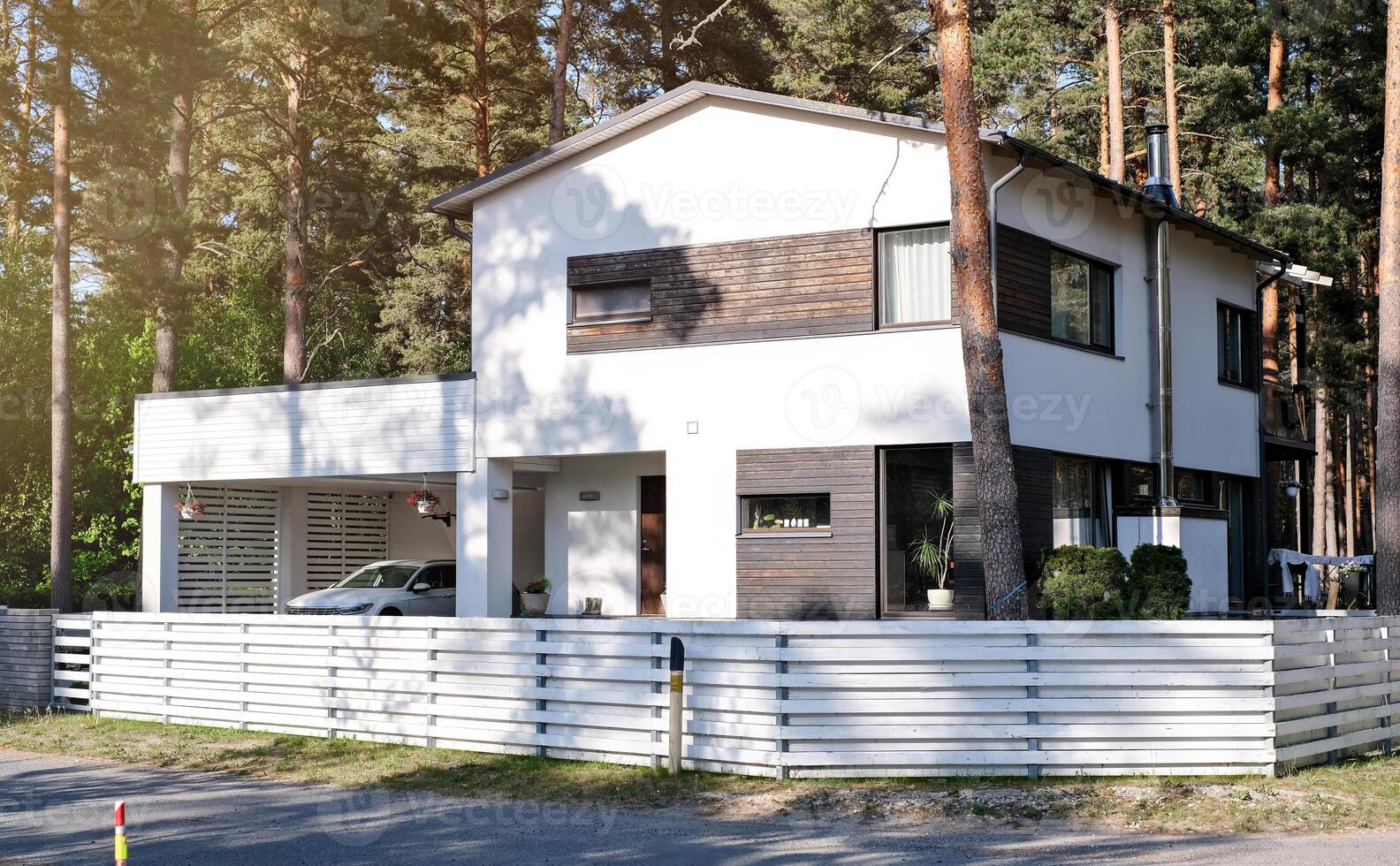 Residential house with a white painted exterior, parked car, and a neat green lawn photo
