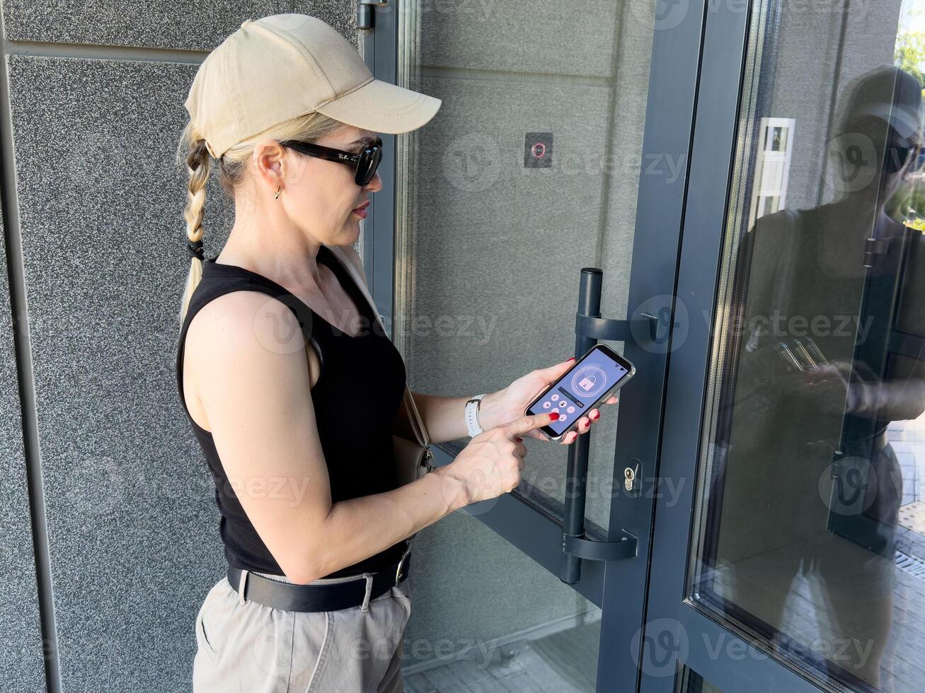 Woman locking smartlock on the entrance door using a smart phone. Concept of using smart electronic locks with keyless access. photo