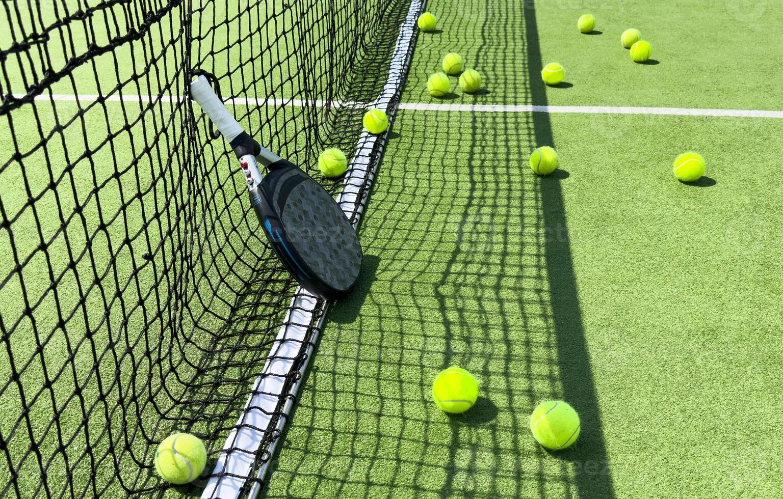 Paddle tennis racket, ball and net on the grass photo
