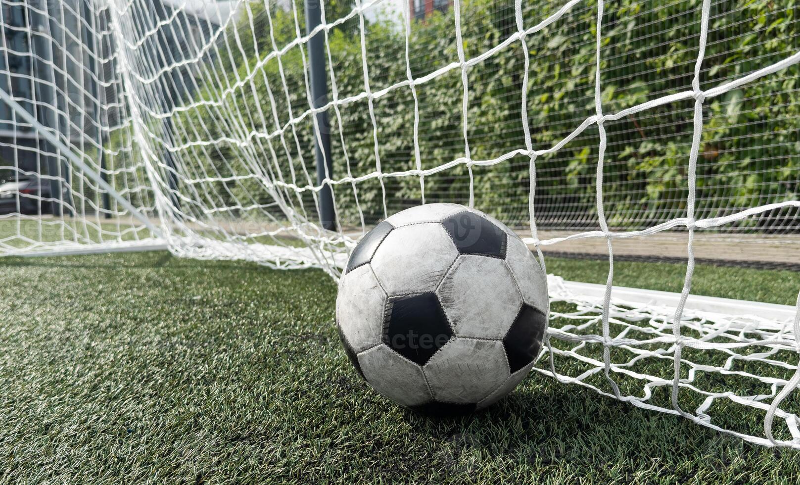 Soccer football in Goal net with green grass field. photo
