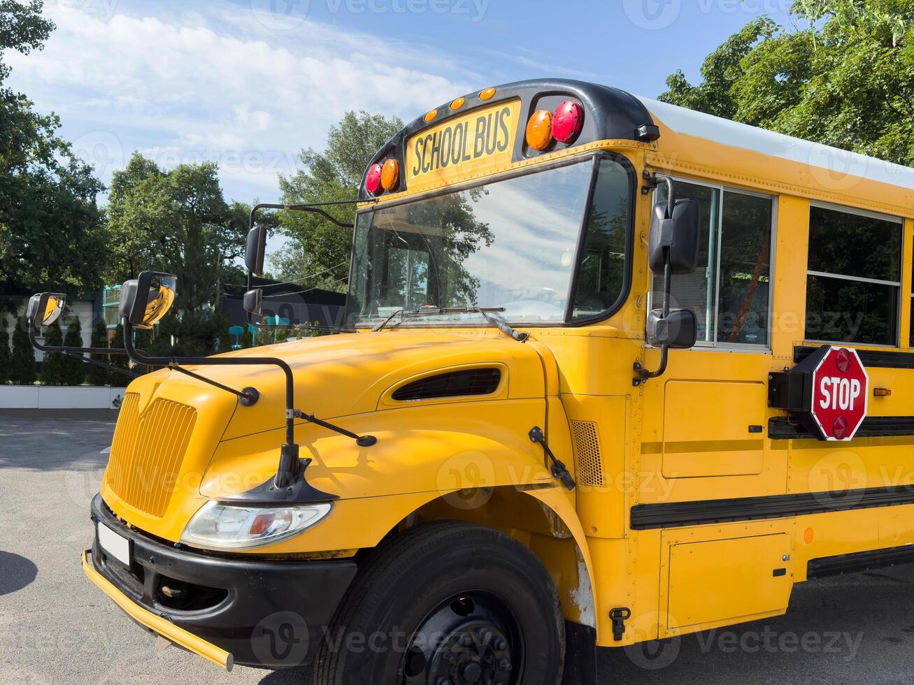 Shot of retro-styled yellow school bus with extended red stop sign standing still on serene road, empty vehicle with no driver awaiting children to boarding, transportation concept, copy space photo