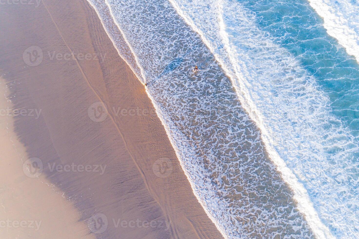 two young men on the shore of the beach at dawn with their surfboards, surfers enjoying the summertime. Overhead view with drone photo