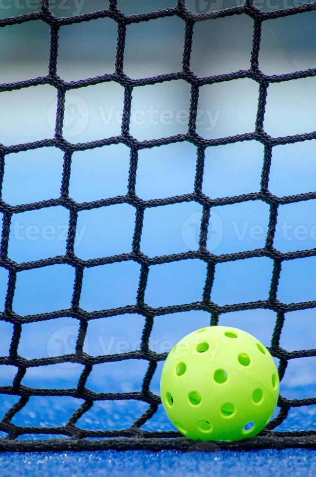 green pickleball ball next to the net of a pickleball court, new racket sport photo