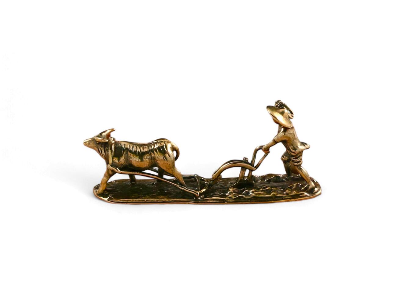 decorative statue of a person plowing a field with a cow on a white background photo
