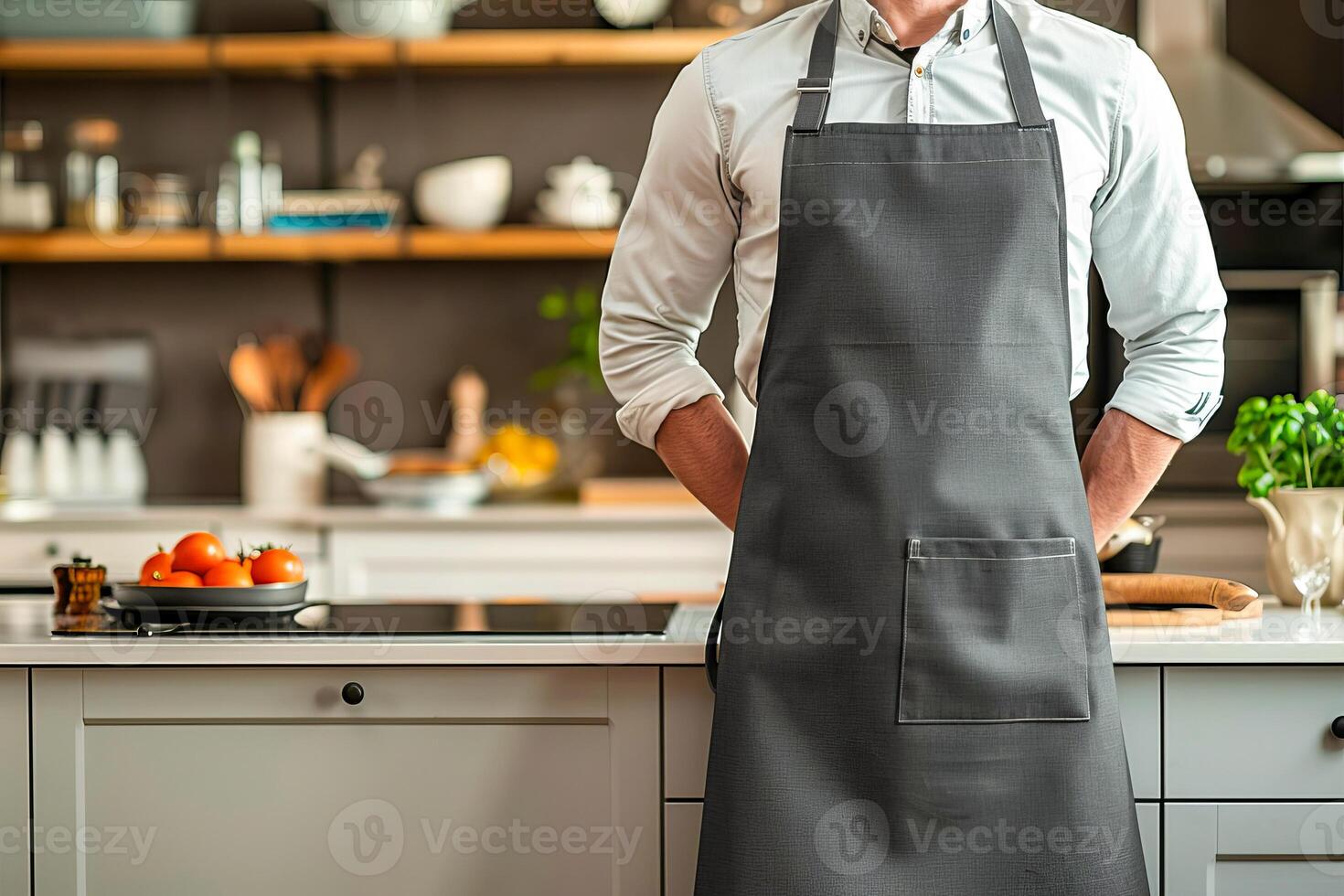 A chef wearing a dark gray linen-cotton apron stands in front of kitchen counter photo