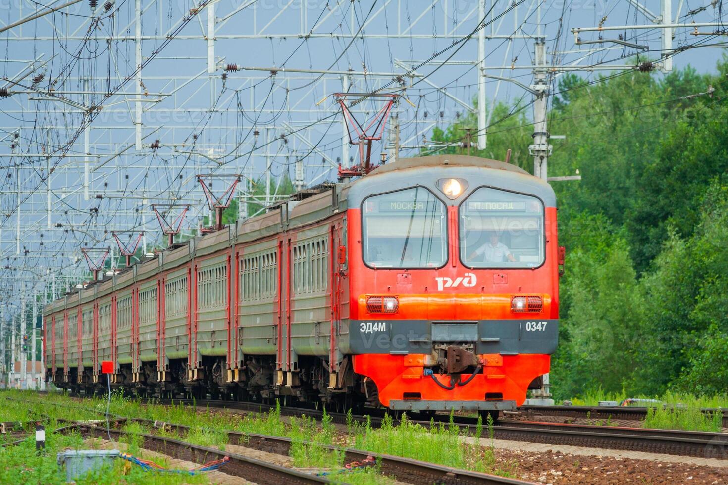 Moscow region, Russia, July 2018 Passenger electric train of the Russian Railways ED4M moves against a green trees photo