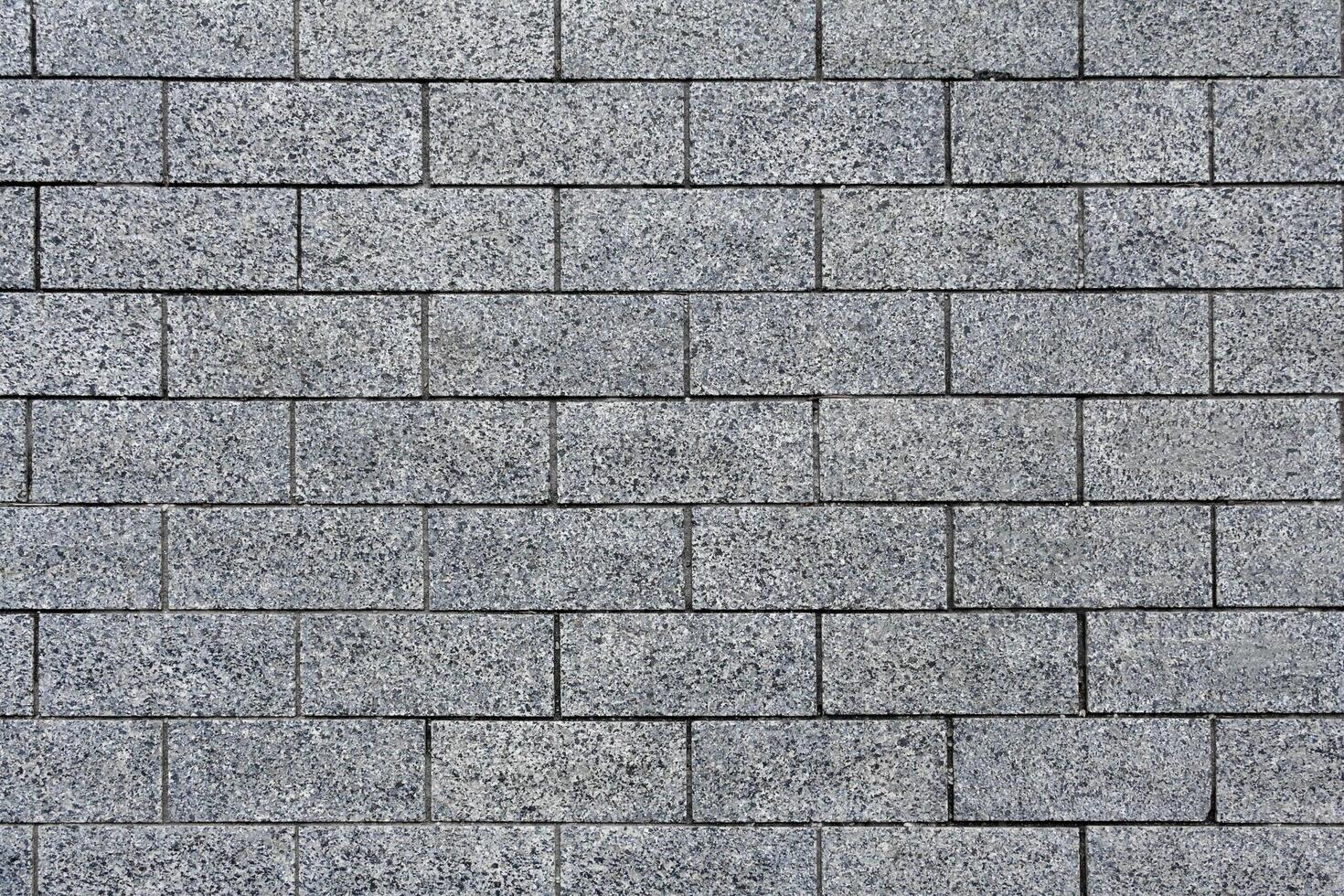 Top view on a gray pavement of granite tiles as texture, background photo