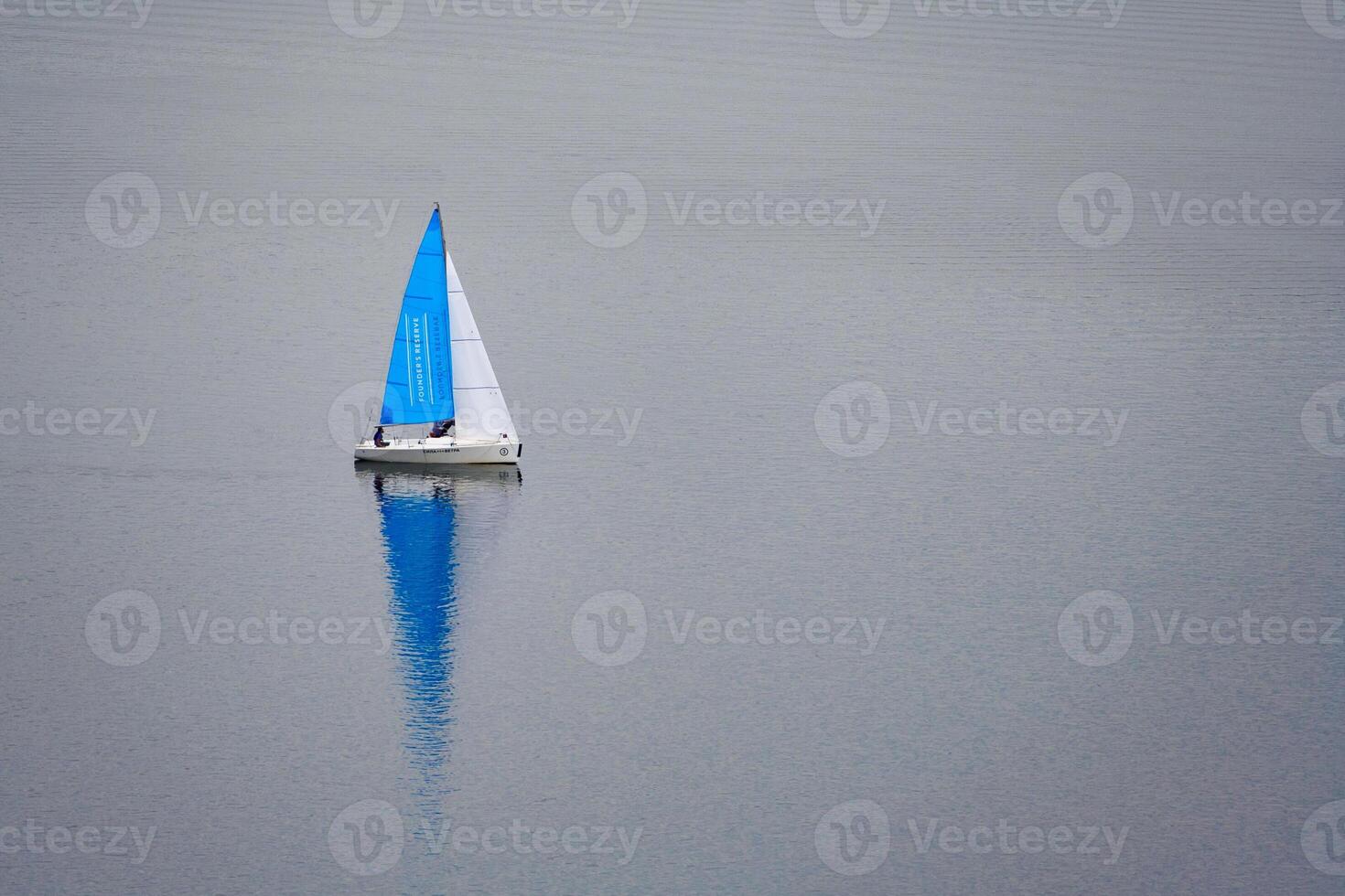 A small sailing boat on the gray water photo