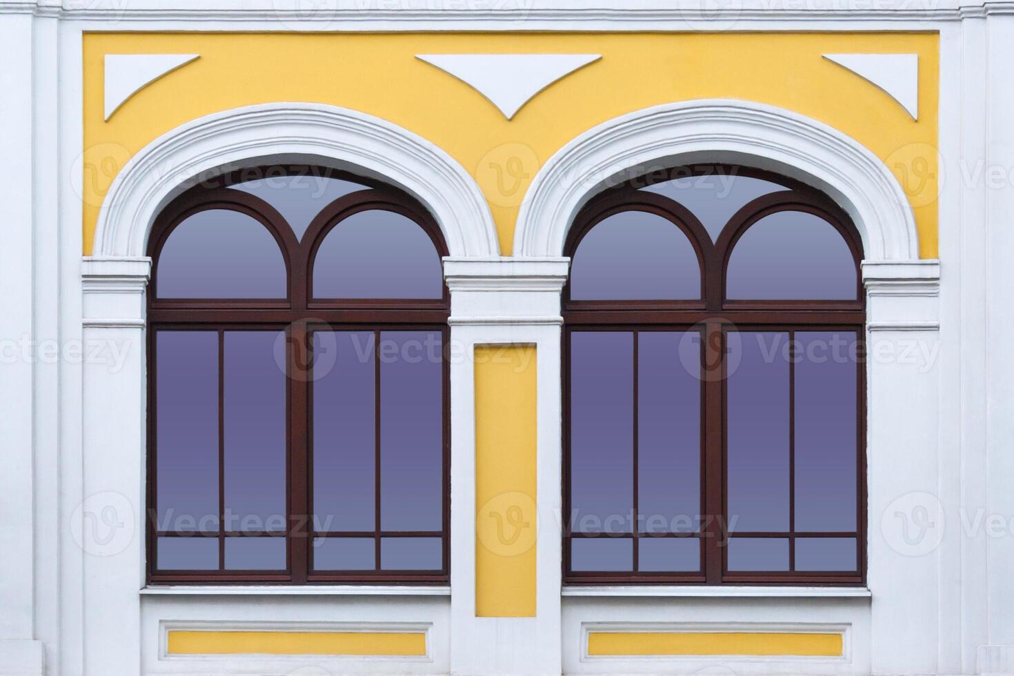 Close up view on a facade of white yellow ancient building with two arched windows as texture photo