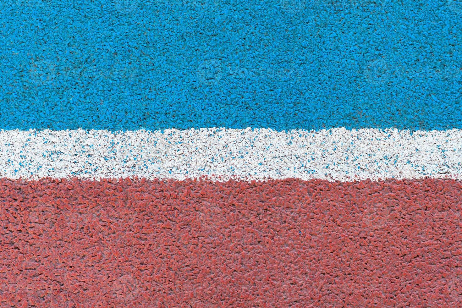 Blue - red tartan surface of athletics stadium with white horizontal line in the middle as texture, background photo
