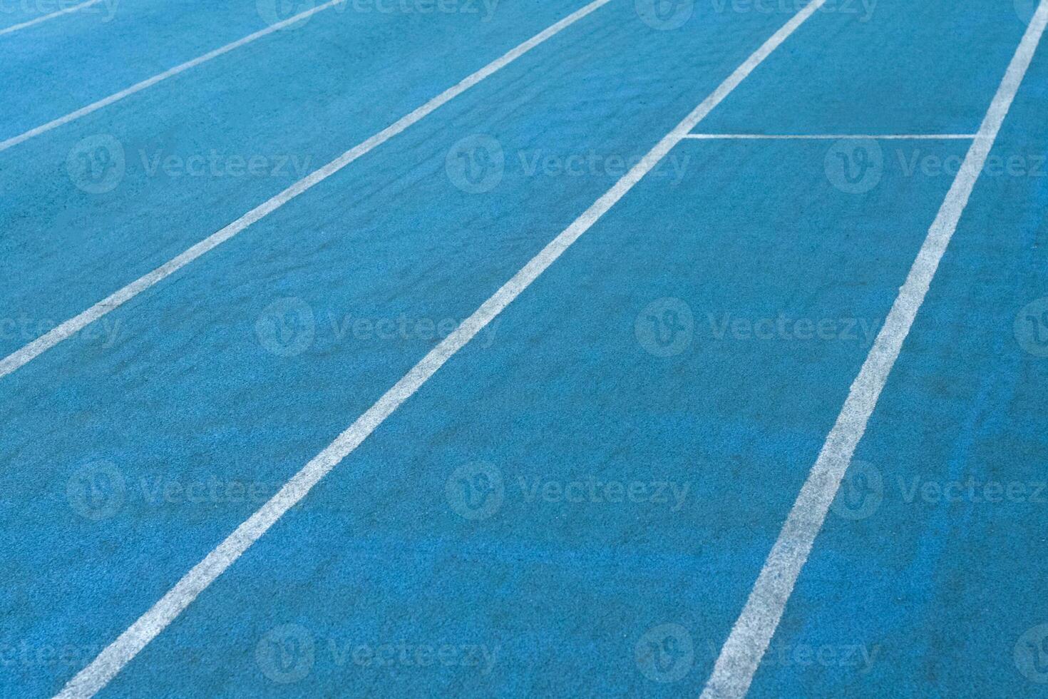 Fragment of blue synthetic surface of running tracks of athletics stadium with white lines as texture, background photo