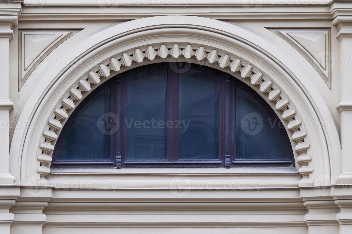 Close up view on a semicircular window on a facade of white stone ancient building with carved decor photo