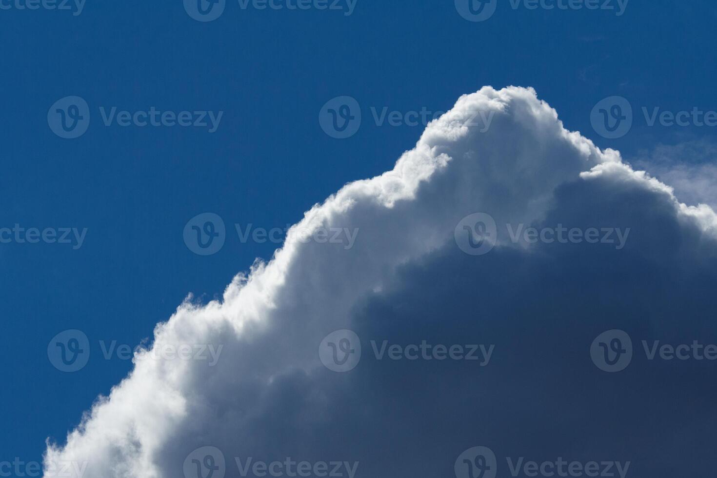 Fragment of a dark fluffy clouds with highlighted edges in the deep blue sky photo