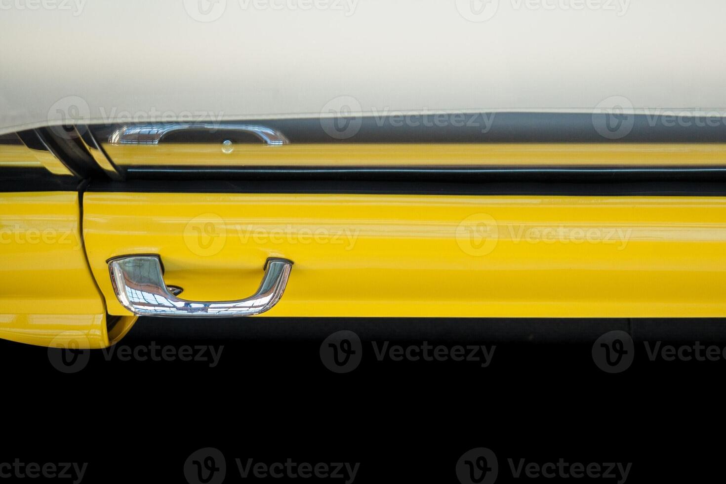 Top view of the door of a yellow car with a chrome handle on a black background. Exhibition of retro cars. photo