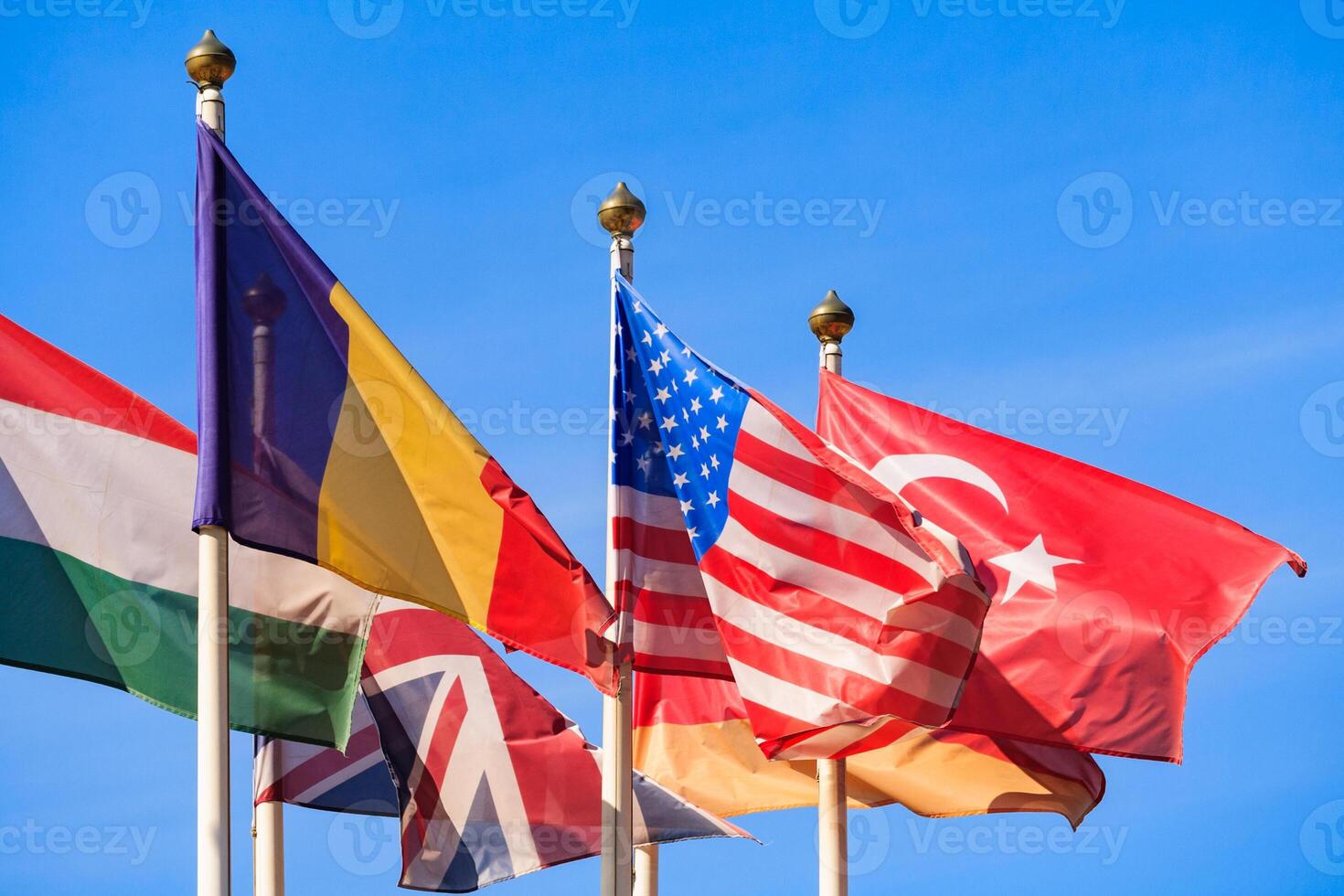 Close up view of a flags of different countries flutters in the wind against a blue sky photo