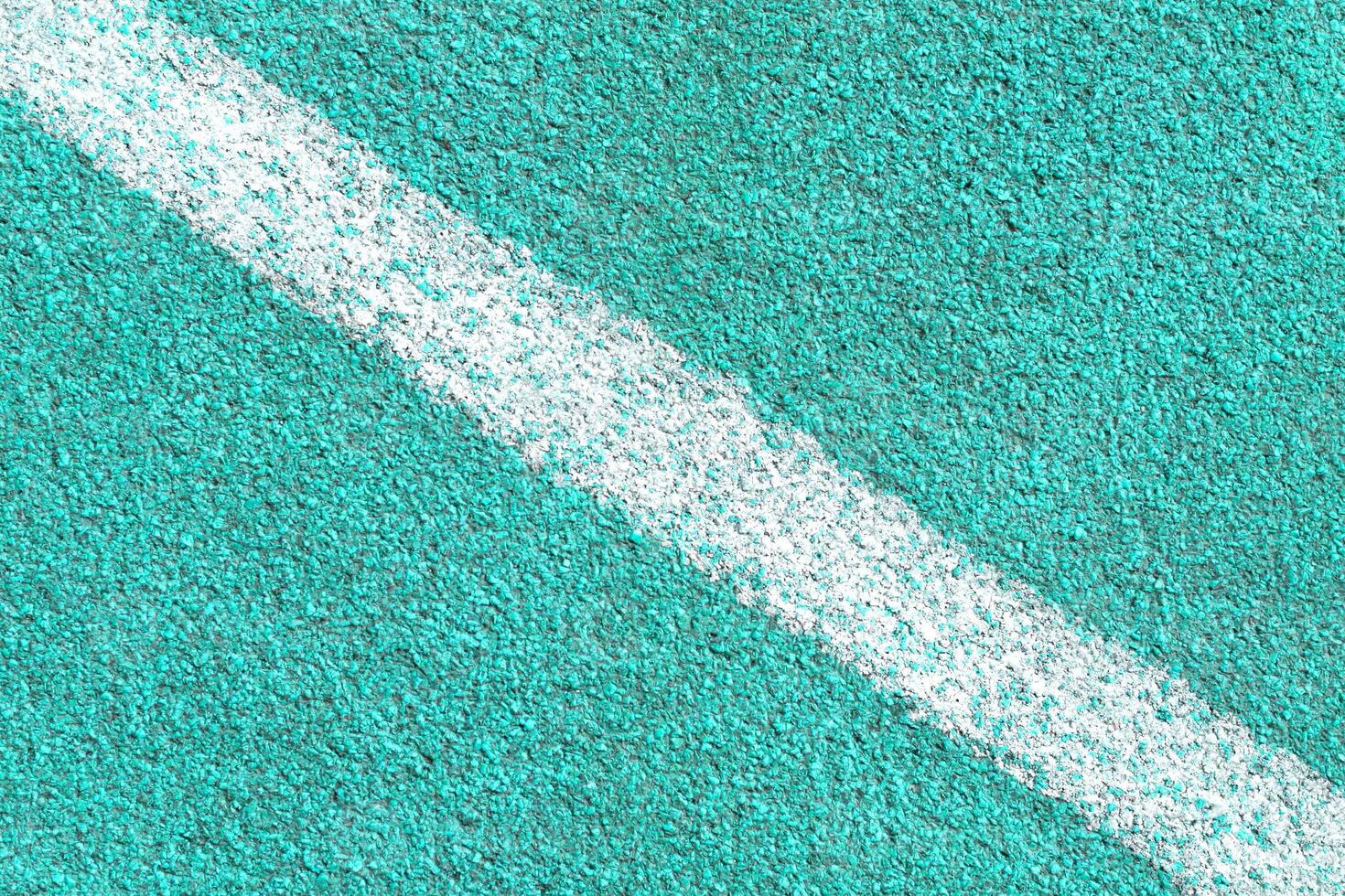 Turquoise synthetic surface of a track of athletics stadium with white diagonal line as texture photo
