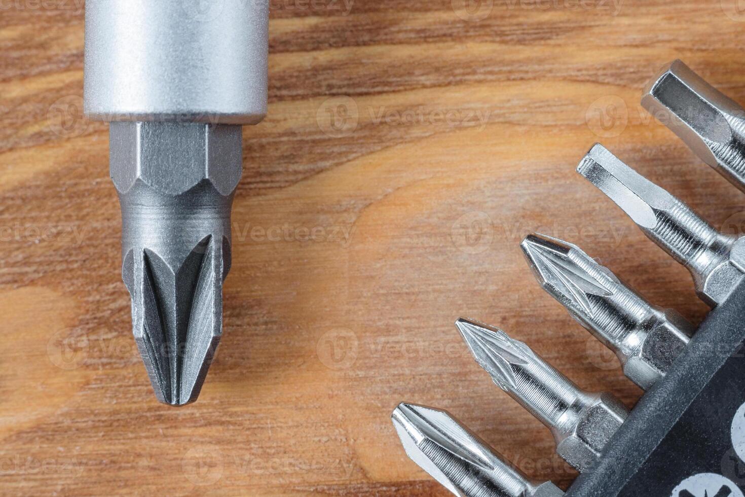Set of heads or bits and screwdriver on a wooden table photo