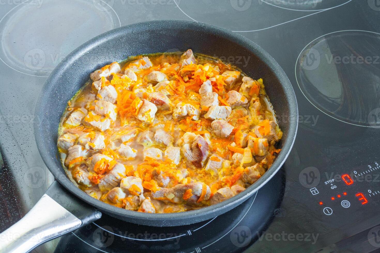Meat with vegetables is stewed in a frying pan photo