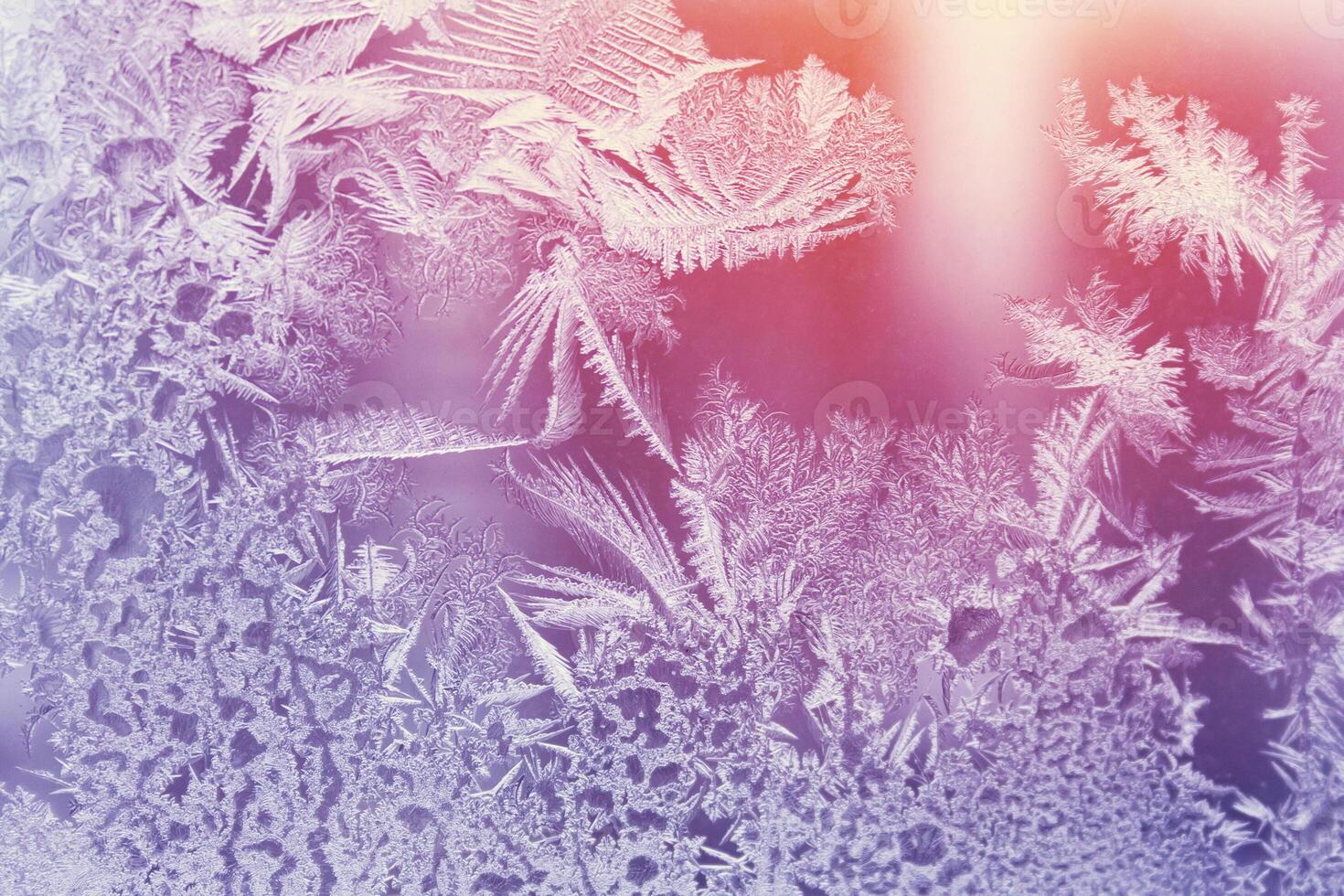 Frosty pattern on the glass window illuminated by sunlight. Abstract, background, toned photo