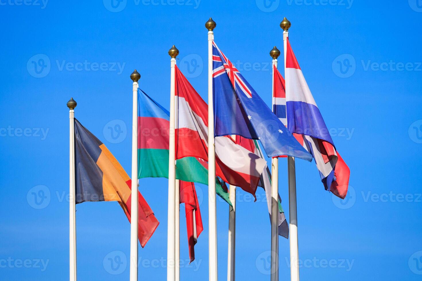 Flags of different countries flutters in the wind against a bright blue sky photo